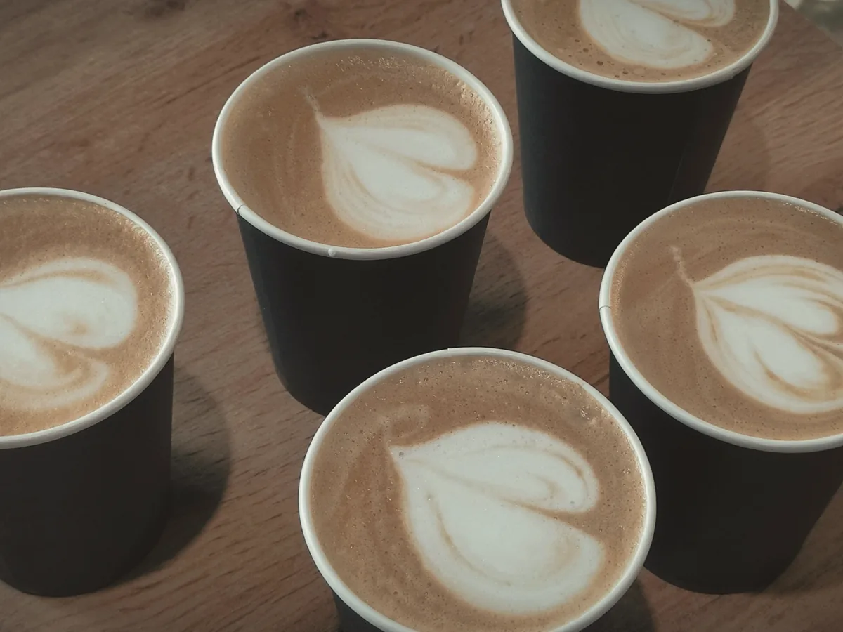 Four coffees with latte art gathered on a wooden table