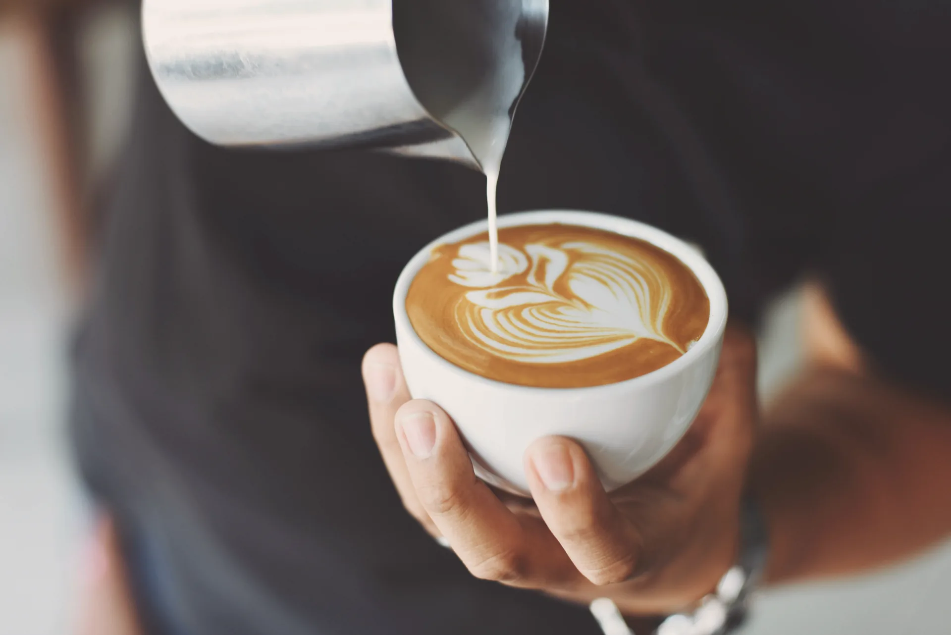 Fresh latte art being poured into a ceramic cup